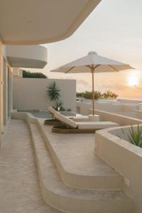 an outdoor patio with an umbrella and a pool at Nour Uluwatu in Uluwatu