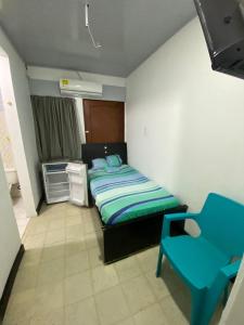 a small bedroom with a bed and a blue chair at Hostal Ferdiz in Montería +6 photos