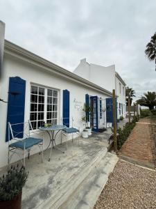 ein weißes Gebäude mit blauen Türen und einem Tisch und Stühlen in der Unterkunft Rosemarys Cottage in Koringberg