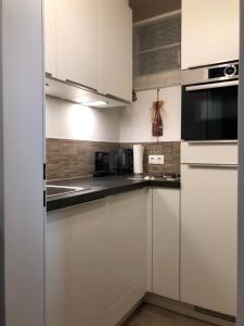a white kitchen with white cabinets and a microwave at appartement Landhaus Osttirol in Iselsberg