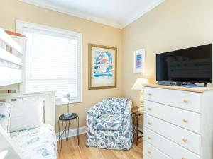 a bedroom with a dresser with a tv and a chair at Brass Rail 214 in Tybee Island