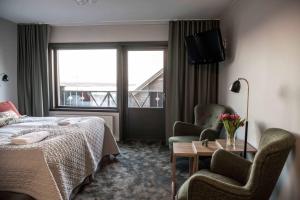 a hotel room with a bed and two chairs and a window at Green Hotel in Tällberg