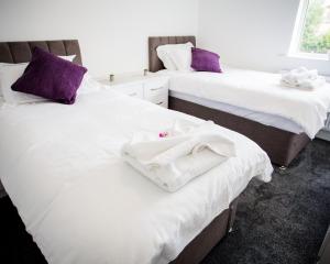 a room with two beds with white sheets and purple pillows at Halford House 3 Bed Town Centre Home from Home with Parking for 2 cars Prime Location Tamworth in Tamworth