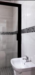 a white bathroom with a sink and a shower at Nyakhosi Luxury Guesthouse in Thohoyandou