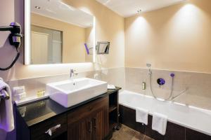 a bathroom with a sink, mirror, and bathtub at Wellnesshotel Cervosa in Serfaus
