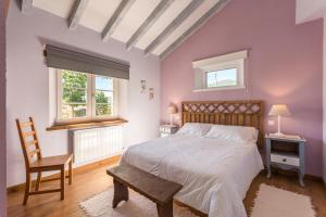 a bedroom with a bed and a chair and two windows at Complejo Abiada Rural in Abiada
