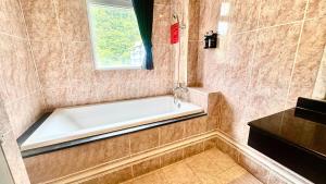 a bath tub in a bathroom with a window at 意大利溫泉會館 in Jiaoxi