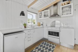 a white kitchen with white appliances and a window at 5590-Svaneke-Duebakken-14 in Svaneke +15 photos