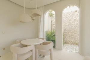 a white dining room with a white table and chairs at NOUR Uluwatu in Uluwatu +16 photos