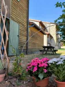 Una mesa de picnic y flores frente a un edificio. en Appartements indépendants dans chalet en Auvergne, en Chomelix