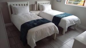 2 Betten in einem Zimmer mit weißer Bettwäsche und blauen Decken in der Unterkunft Jay's Snug in Knysna