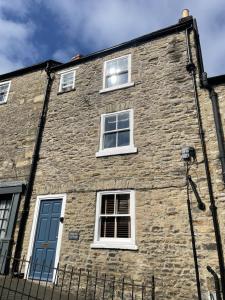 un bâtiment en briques avec trois fenêtres et une porte bleue dans l'établissement Millgate Cottage in the heart of Richmond, à Richmond