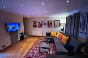 a living room with a couch and a flat screen tv at Stylish Stratford upon Avon Stay - Gated Parking - Sleeps 6 in Stratford-upon-Avon +35 photos