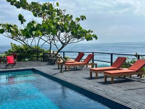 ein Pool mit Stühlen und das Meer im Hintergrund in der Unterkunft Finca Barlovento Maloka, Tayrona Park in Los Naranjos