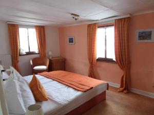 a bedroom with a bed and a chair and windows at Historisches Fachwerkhaus in Reifferscheid