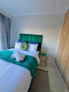 a bedroom with a large bed with a green headboard at Blyde Lagoon in Pretoria