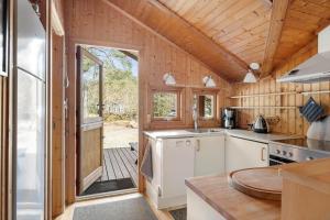 a kitchen with white appliances and a wooden wall at 2544-Nexo-Skovsangervej-29 in Neksø +11 photos
