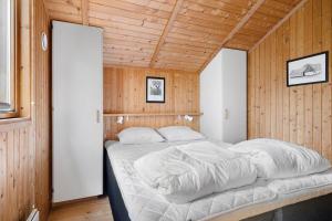 a large bed in a room with wooden walls at 2544-Nexo-Skovsangervej-29 in Neksø