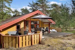 a yellow house with a deck and an umbrella at 2544-Nexo-Skovsangervej-29 in Neksø