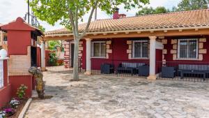 a red house with black chairs in the courtyard at Casas Rurales Ramírez in Ossa de Montiel +8 photos
