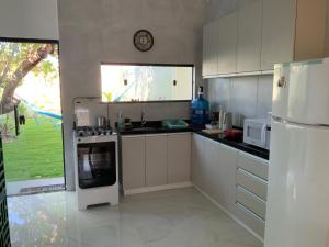 eine Küche mit weißen Schränken und einem weißen Kühlschrank in der Unterkunft Casa dos cajueiros in Paracuru