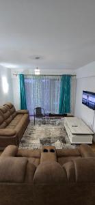 Una sala de estar con un sofá y un televisor. en The Glass Loft, en Nairobi