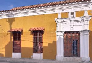 a yellow building with two doors and two windows at Casa Digna in Cartagena de Indias