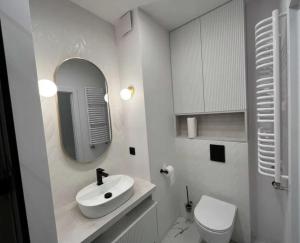 a white bathroom with a sink and a toilet at Kosynierów 12 Apartment in Marki
