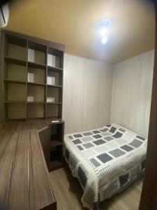 ein Schlafzimmer mit einem Bett und einem Bücherregal in der Unterkunft Apartamento central confortável in Pelotas + 3 Fotos