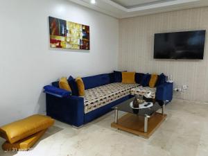 a living room with a blue couch and a table at Appart Haut Standing, Très Calm à Nouaceur, Parking, Piscine, à 4min de l'Aéroport in Casablanca