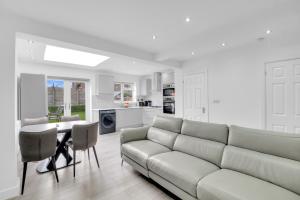 Una sala de estar blanca con un sofá y una mesa. en 4 Bed - Sleeps 8 - Free Parking - Garden, en Dagenham