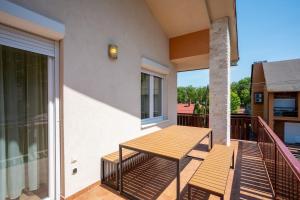 een patio met een houten tafel en een balkon bij Avanti Apartman - Avanti Tutti in Balatonboglár