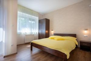 een slaapkamer met een bed met gele lakens en een raam bij Avanti Apartman - Avanti Tutti in Balatonboglár
