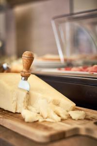 a block of cheese on a cutting board with a knife at Hotel Tre Ville in Parma
