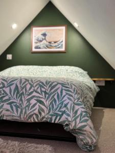 a bed in a room with a green wall at Braelea cozy - country out building with mezzanine in Hamnavoe