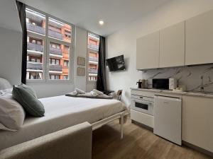 a bedroom with a bed and a kitchen with white cabinets at Gabika Apartment 2 in Bilbao