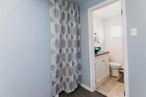 a bathroom with a toilet and a shower curtain at Avenir Centre Suite - Near NBCC - Large Garden in Moncton +10 photos