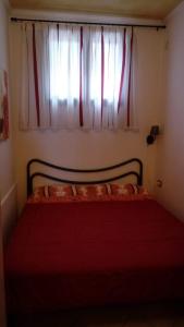 Un dormitorio con una cama roja con una ventana. en Appartamento Mariolu 2, en Santa Maria Navarrese