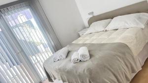 - un lit avec des serviettes et une fenêtre dans l'établissement Los Soles de Madryn, à Puerto Madryn