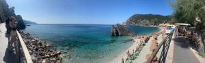 a beach with umbrellas and people in the water at Da Vice Rooms in Monterosso al Mare