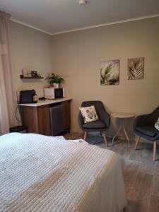a bedroom with a bed and two chairs and a table at Kattugglans Gästrum 2 in Ljungby