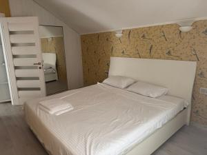 Un dormitorio con una cama blanca y un espejo. en Fortuna Mare, en Odessa