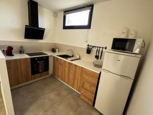 a kitchen with a white refrigerator and a sink at Entre Campagne et Ville in Marcorignan +2 photos