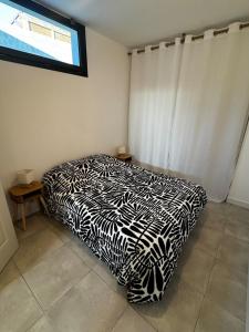 a black and white bed in a room with a window at Entre Campagne et Ville in Marcorignan