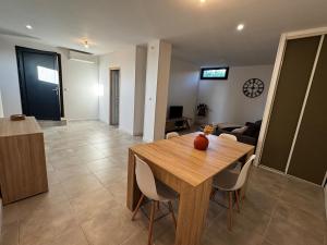 a dining room and living room with a wooden table and chairs at Entre Campagne et Ville in Marcorignan