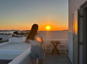 a woman standing on a balcony watching the sunset at Farous seaside sunset villa II in Andiparos