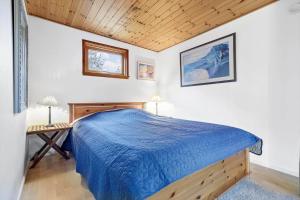 a bedroom with a blue bed and a wooden ceiling at 4759-Ronne-Stampen-Vej-1-Hus-4 in Rønne