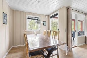 ein Esszimmer mit einem Tisch und einigen Fenstern in der Unterkunft 1512 Aakirkeby - Bjælkeåsen 3 in Vester Sømarken + 13 Fotos