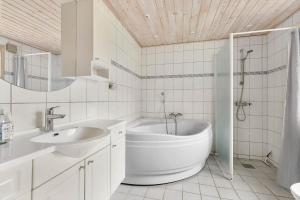 ein weißes Badezimmer mit Badewanne und Waschbecken in der Unterkunft 1512 Aakirkeby - Bjælkeåsen 3 in Vester Sømarken