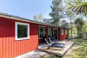 ein rotes Haus mit einer Terrasse und Stühlen darauf in der Unterkunft 1512 Aakirkeby - Bjælkeåsen 3 in Vester Sømarken